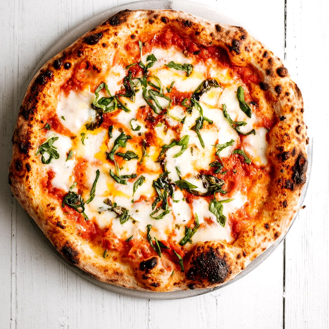 Knusprige Pizza mit geschmolzenem Käse, Tomaten und Kräutern