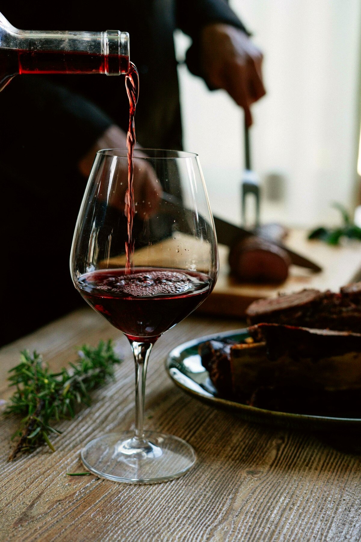 Rotwein wird in ein Glas eingeschenkt