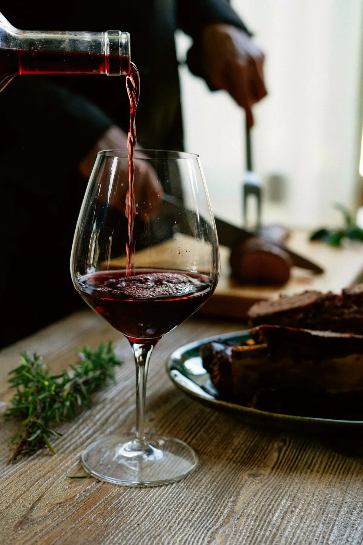 Rotwein wird in ein Glas eingeschenkt