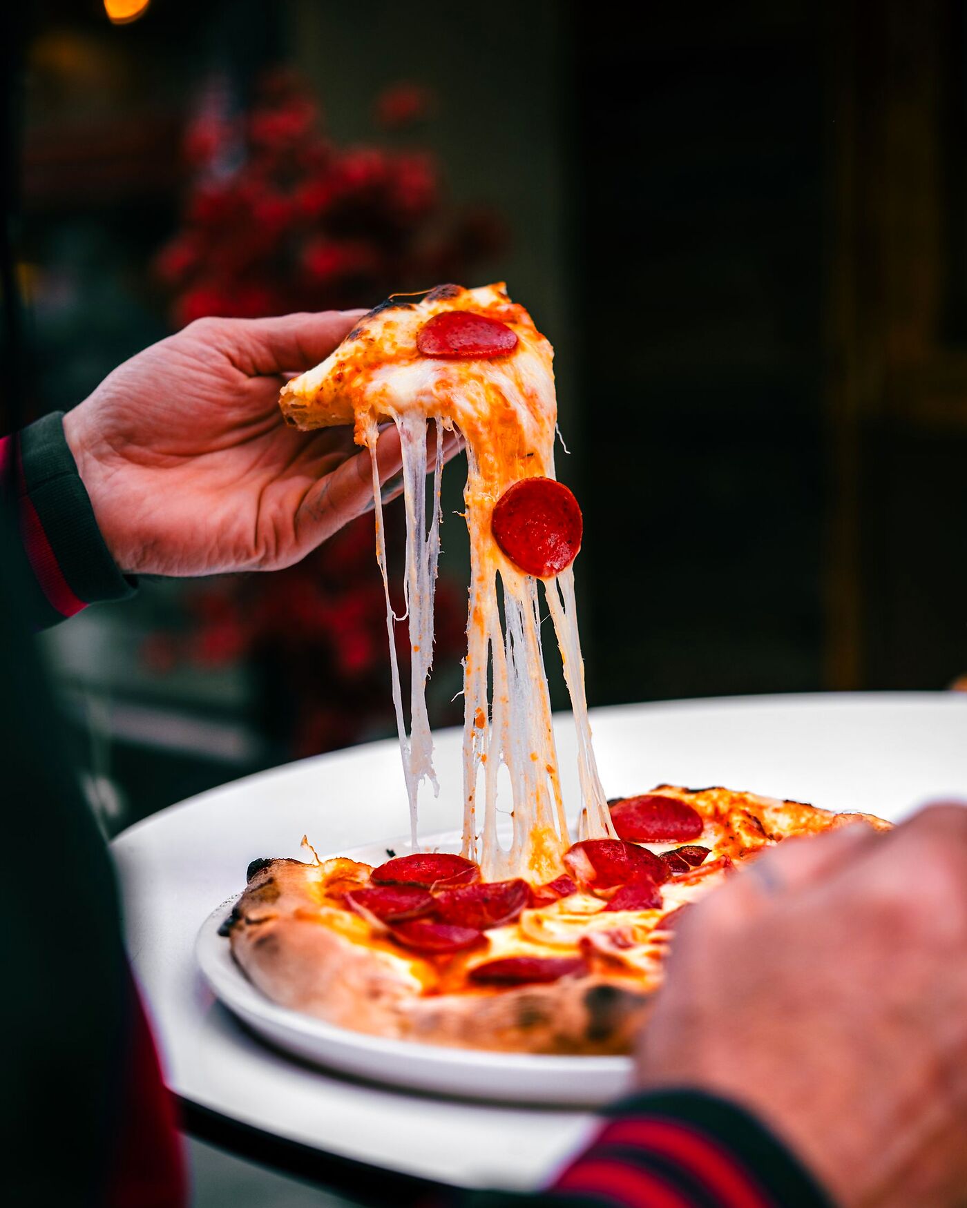 Ein Stück Salamipizza wird abgehoben, der Käse zieht lange Fäden